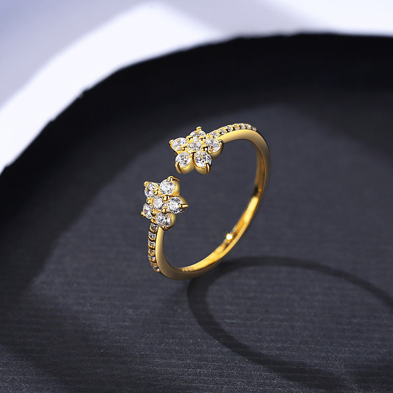 double flower Gold ring with cubic zirconia accents on a dark fabric background