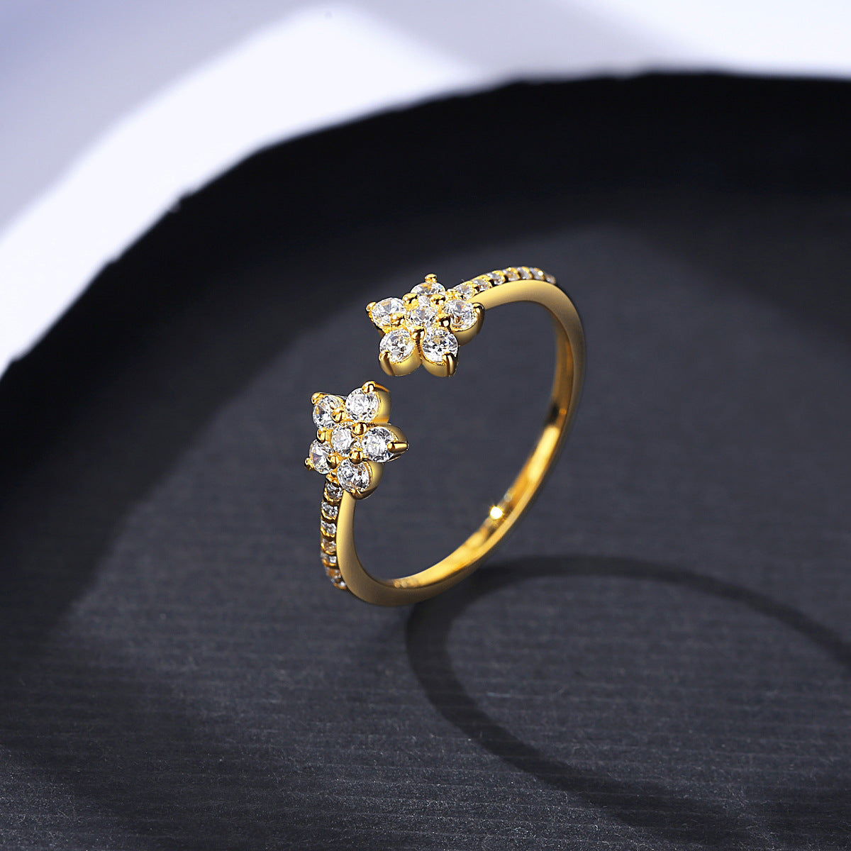 yellow Gold ring with floral designs on a dark fabric background