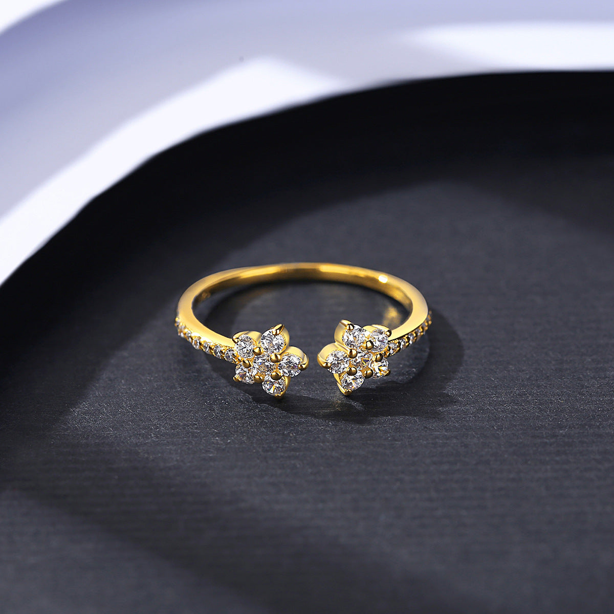 Gold ring with floral design on a dark surface with adjustable band