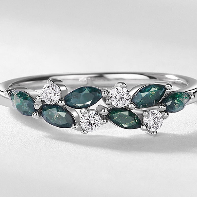 Silver ring with alternating marquise moss agate and round cubic zirconia, close - up on white, stylish jewelry piece