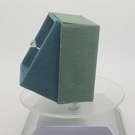 Emerald green CZ ring display in a green velvet box rotationally on desk